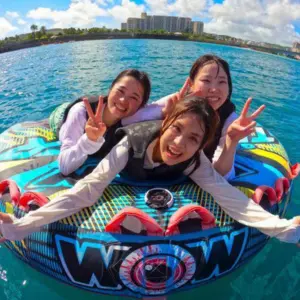 海の上に浮かんでいるウォータートイに女性3人がのって楽しんでいる