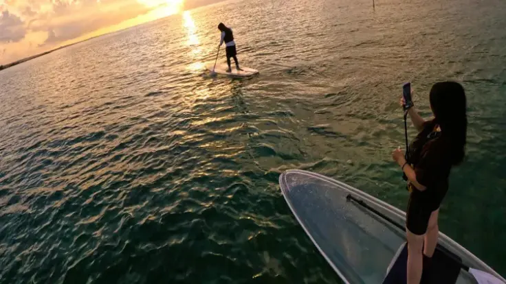 沖縄の海でサンセットSUPを楽しむ様子。夕日を眺めながら海上でゆったり過ごす贅沢な時間。