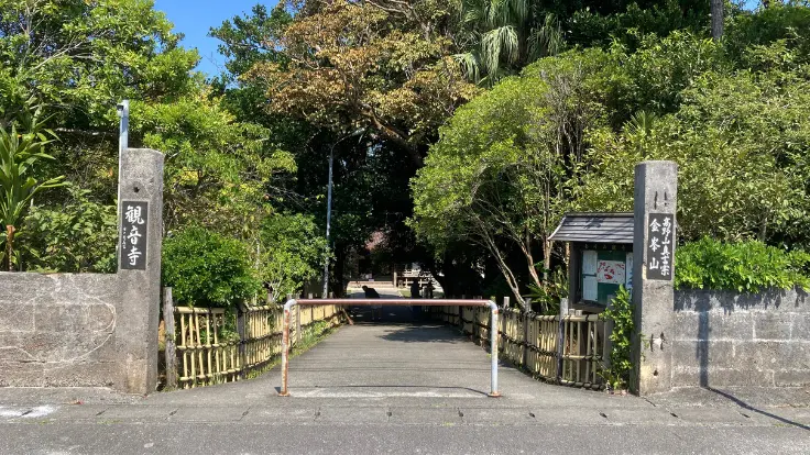 金武観音寺の山門と参道。石畳の先に本堂が見え、静かな緑に包まれた境内が広がる。