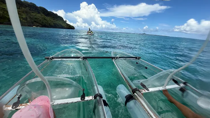 水上バイクに引かれて進むグラスカヤックで、家族連れが海を楽しんでいる様子。