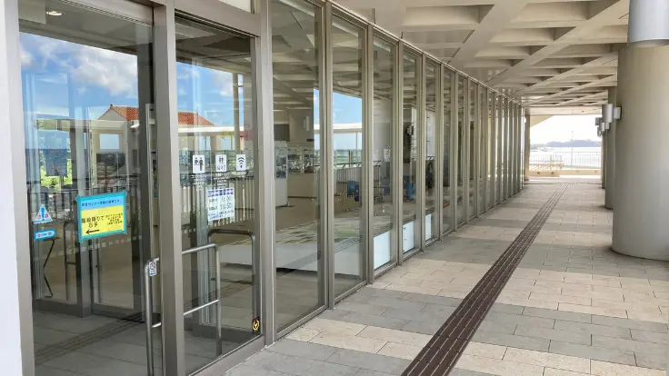 道の駅許田の向かいにあるターミナル2階休憩室の入り口外観。ガラス張りの扉と案内板が目印で、人も少なく静かに過ごせる。