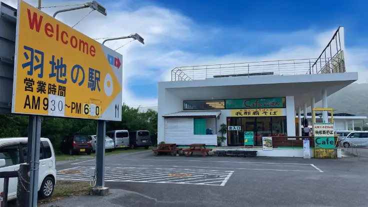羽地の自然を背景にした『道の駅羽地』の看板。青空に映える清潔感あるデザインが印象的。