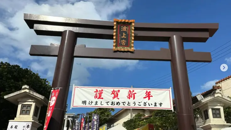 元旦の波上宮一の鳥居。『謹賀新年』の垂れ幕が掲げられ、多くの参拝者が新年の祈りを捧げている。