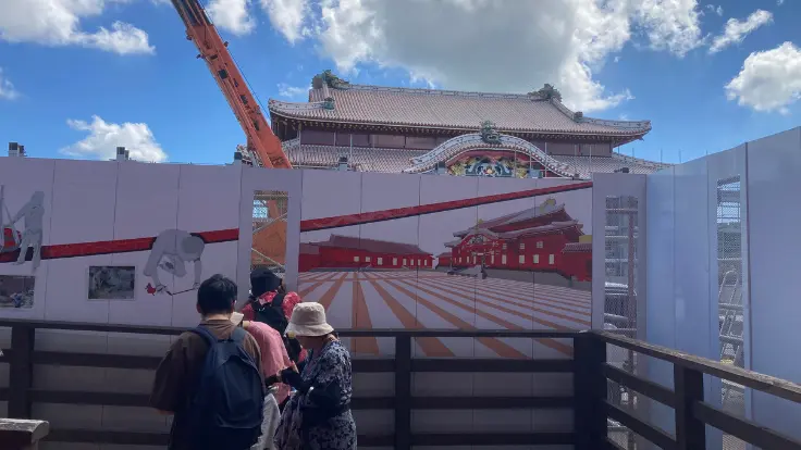 首里城入り口すぐ。素屋根が外れ工事壁で囲まれた正殿がうっすら見える様子