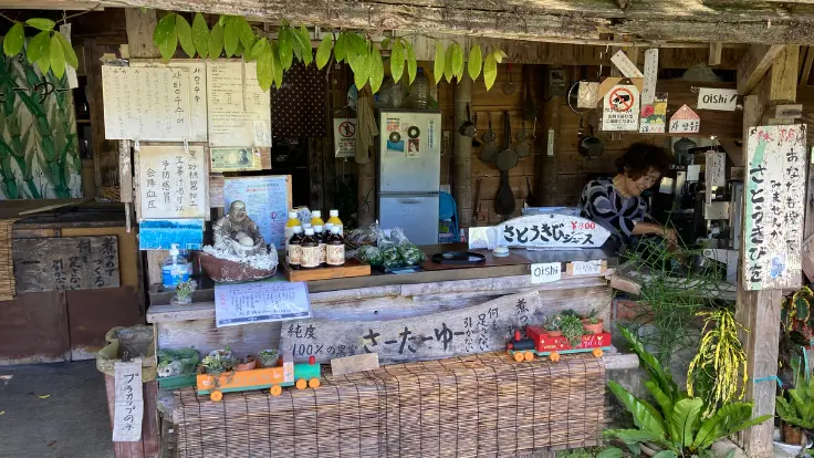今帰仁城跡入口でさとうきびジュースを販売するおばぁ。素朴な笑顔と手しぼりの雰囲気が温かい。