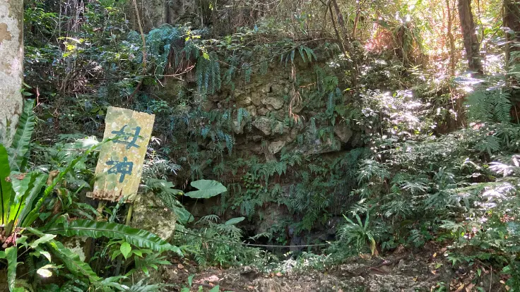 ガンガラーの谷のイナグ洞入口に立つ「母神」の札。地元のシャーマン(ユタ)が独自に立てたもので、女性を象徴する御神体として安産や良縁の祈りが込められてきた。