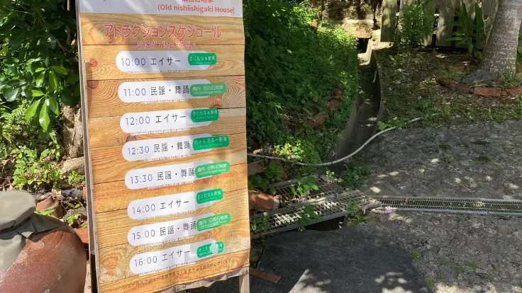 琉球村の園内に設置されたエイサーや琉球舞踊のタイムスケジュール看板。10時から16時までの催しが一覧で紹介されている。