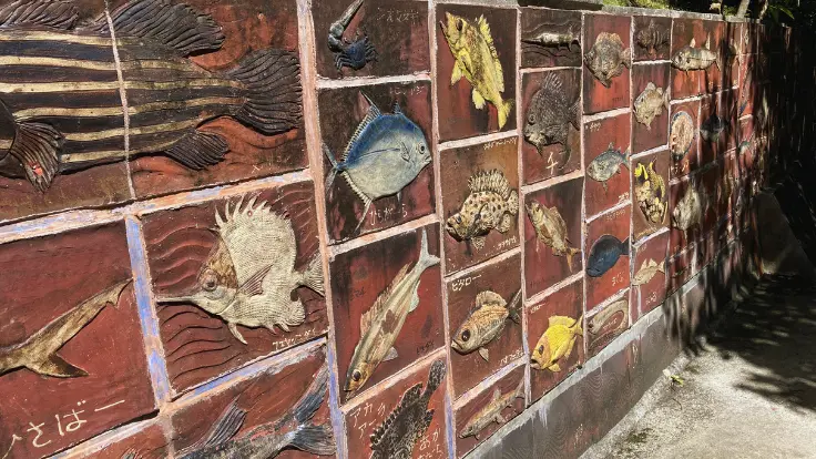琉球村の壁に描かれた沖縄の魚たちのイラスト。カラフルでユーモラスな表情が印象的。