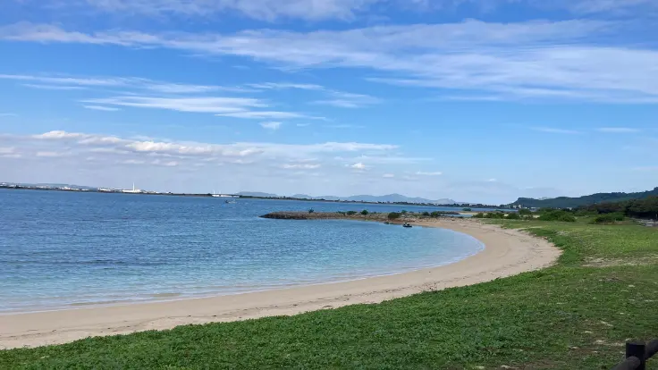 浜比嘉ビーチの白い砂浜と透明度の高い海。波打ち際で足先だけ海につけてのんびり過ごせる、穏やかな雰囲気の浜辺。