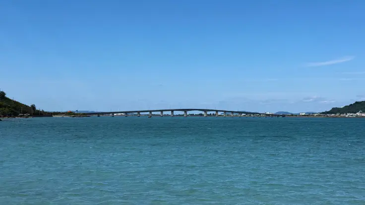 平安座島から浜比嘉島へと続く浜比嘉大橋。浅瀬の海の上にまっすぐ伸び、海中道路の先にある小さな島へ渡る道になっている。