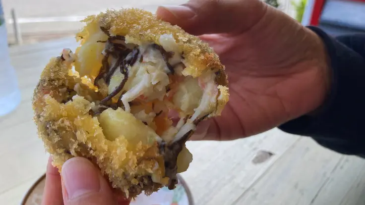 浜比嘉島の丸吉食品で提供される揚げたてのもずくコロッケ。外はサクッと、中はもずくの旨味が広がる人気メニュー。