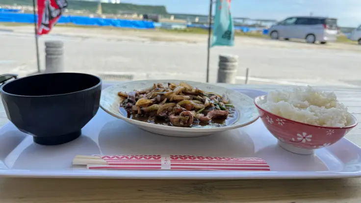 浜比嘉島の丸吉食品で提供されるイカスミ定食。店前のベンチで島風に吹かれながらいただける、素朴でおいしい島ごはん。
