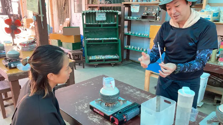 浜比嘉島の高江洲製塩所で、スタッフが参加者の塩づくりを丁寧にサポートしている様子。海水の濃縮工程や仕上げ方をやさしく教えてくれる。