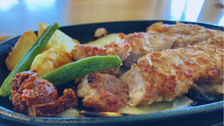 熱々の紅豚ロースステーキが鉄板にのっている
