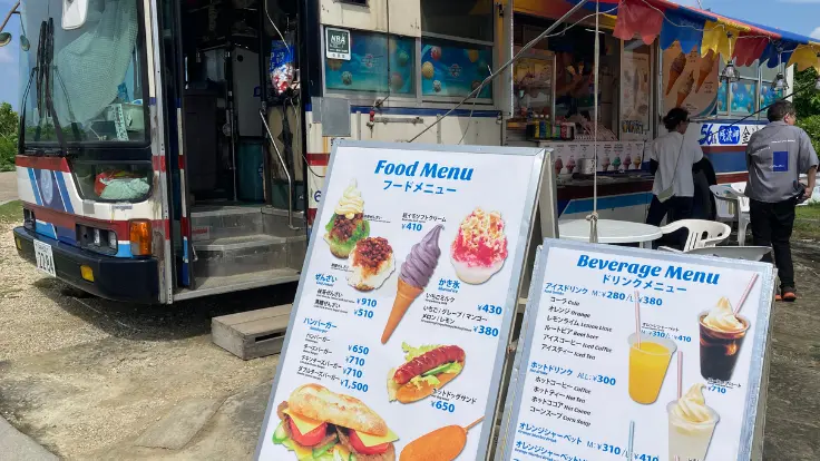 残波岬灯台横にあるバス型の金城パーラー。カラフルなバスとパラソルの下で、軽食やスイーツを楽しめる。