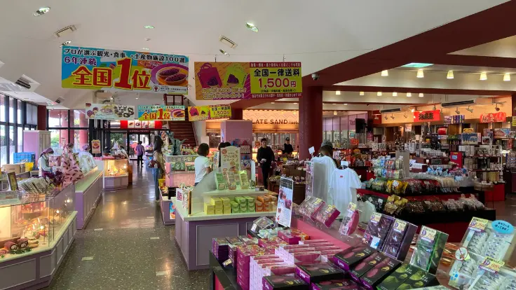 お菓子御殿 読谷本店の店内に並ぶお土産コーナー。紅いもタルトや限定スイーツが美しく陳列されている。