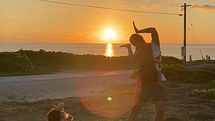 残波岬で夕日に照らされる人物のシルエット。水平線に沈む夕日が幻想的な風景を演出している。