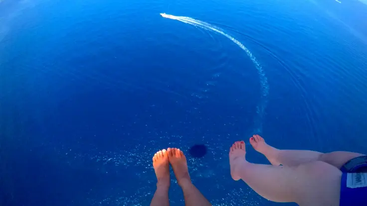 パラセーリング中に上空から足元を見下ろした視点。透明感のある沖縄の海が広がって見える