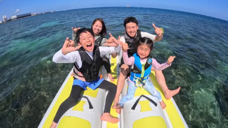 家族がバナナボートの上で笑顔で記念撮影をしている様子
