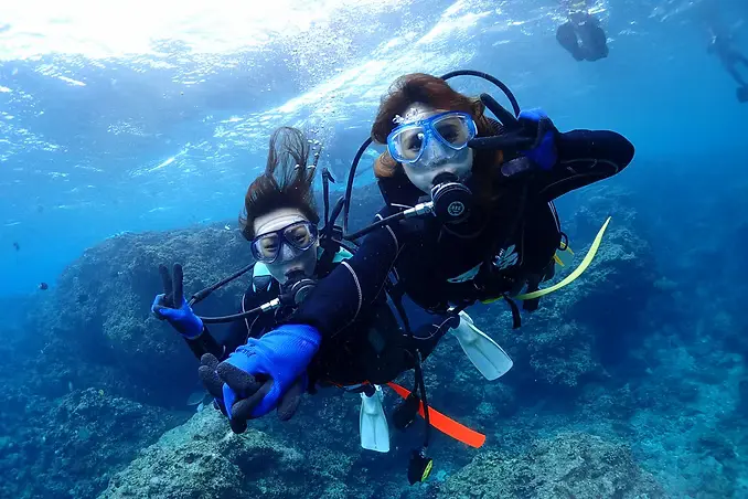 沖縄・真栄田の青い海をバックに水面移動するシマハロの体験ダイビング