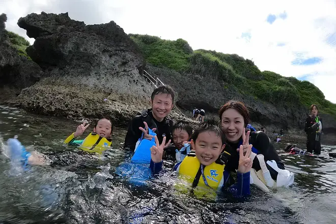 サンゴ礁が広がる海の上を、のんびりとボートで進むゲストと真栄田の青い海