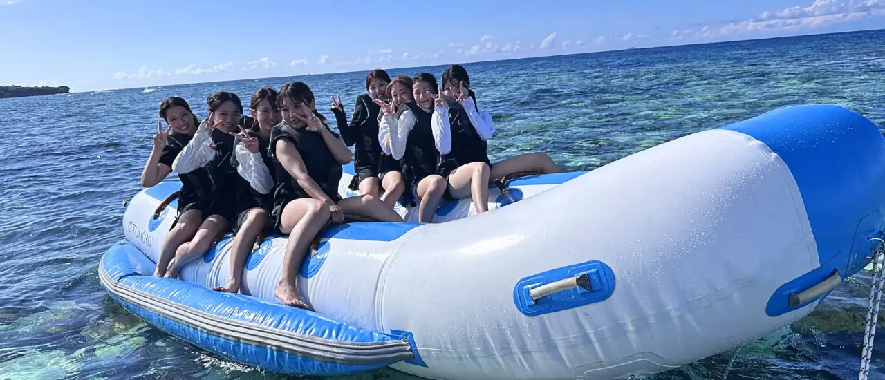 女性の大学生グループが団体でバナナボートを楽しんでいる